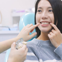 Woman smiling at her dentist and pointing to her teeth