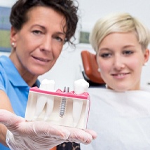 Dentist holding a model of a dental implant.