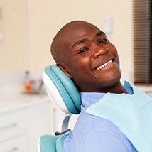 Man in blue shirt smiling while relaxing in dental chair
