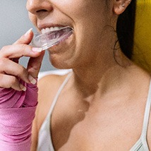 Female boxer placing clear mouthguard in her mouth