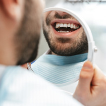 A man admiring his tooth-colored filling in the mirror