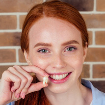 smiling young lady holding a wisdom tooth