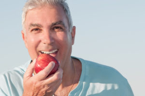 older man smiling eating apple