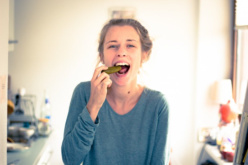 A woman eating a pickle for good dental health